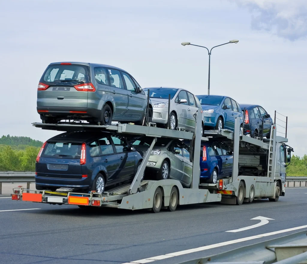 Car carrier truck transporting multiple vehicles on highway for shipping.