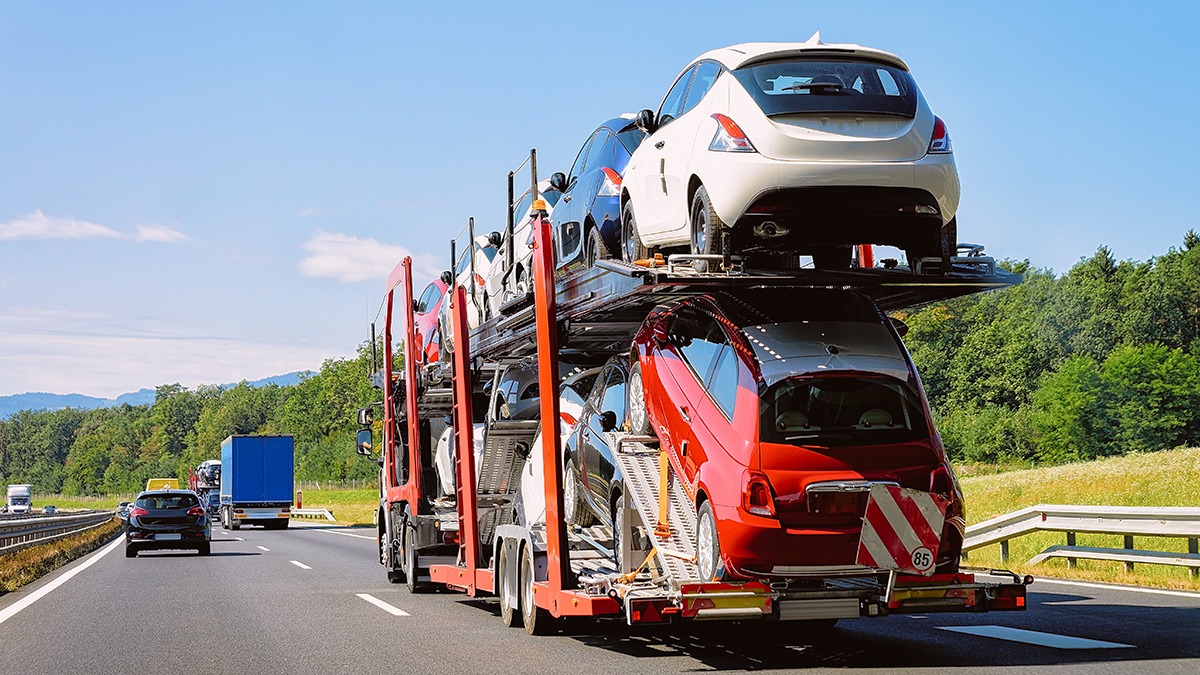 Car carrier truck on highway for specialized vehicle transport USA, loaded with compact cars.
